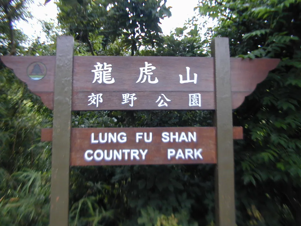 Wooden signboard reading 龍虎山郊野公園 Lung Fu Shan Country Park among trees.