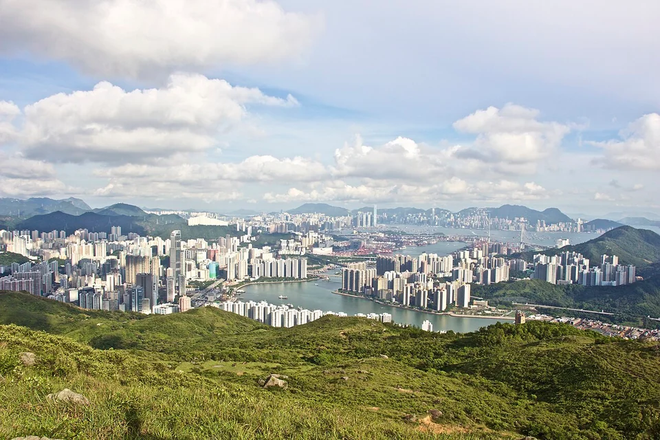 View from a hilltop over Tsuen Wan towers and the harbour, with hills behind.